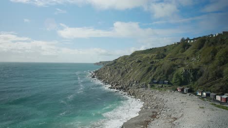 4K-Panoramic-landscape-shot-of-the-beach-and-cliffs-of-Church-Ope-on-the-island-of-Portland,-in-Dorset,-England,-on-a-beautiful-sunny-day,-against-the-sun