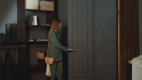 young female in business suit comes home carrying bags