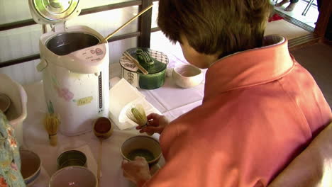 mujer japonesa prepara té verde matcha con batidor de bambú y cucharón