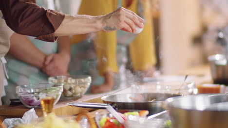 chef salting food on pan during cooking master class