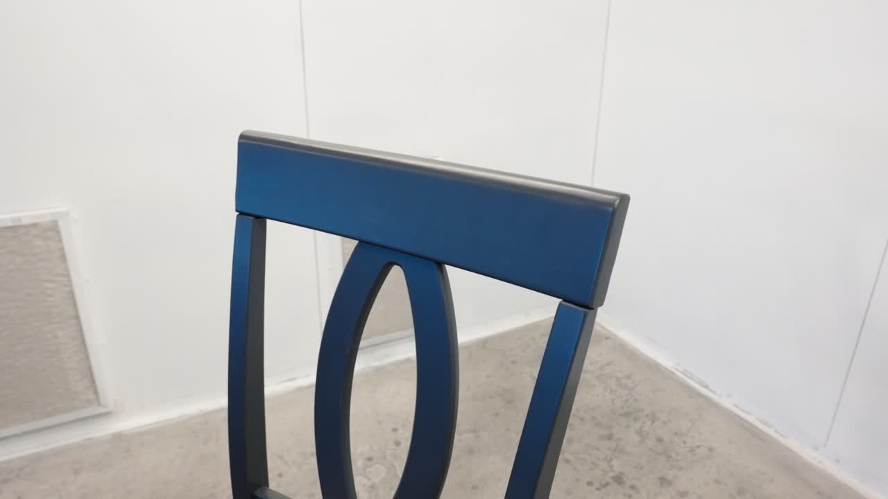 Close view of grey wooden chair back, fresh coat, inside spray enclosure