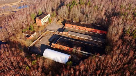 Soviet structures blend into brown forest near Slokas Lake, Ķemeri National Park
