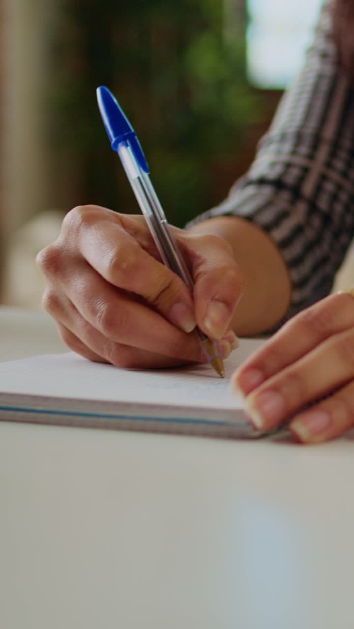 Vertical video Remote worker writing info on paper using pen, close up shot