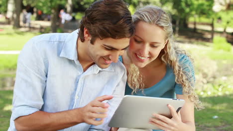 a couple use a tablet together as they then look at the camera