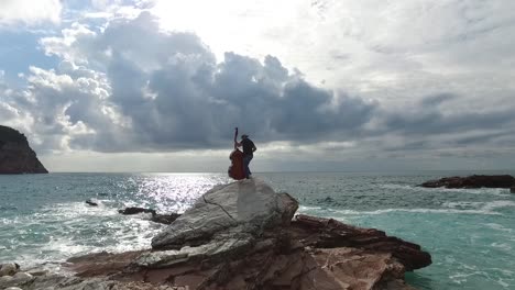 double bass player on a rocky coast