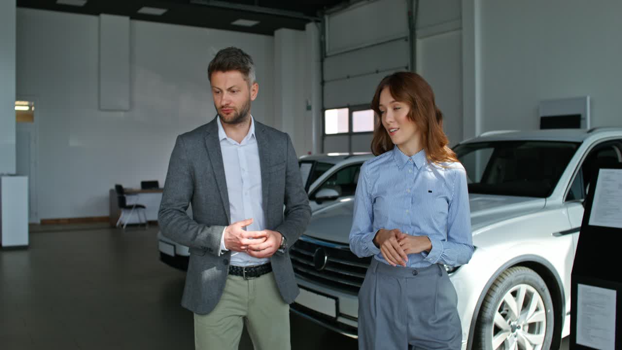 un vendedor de coches y una vendedora discutiendo un coche con un cliente en una sala de exposiciones