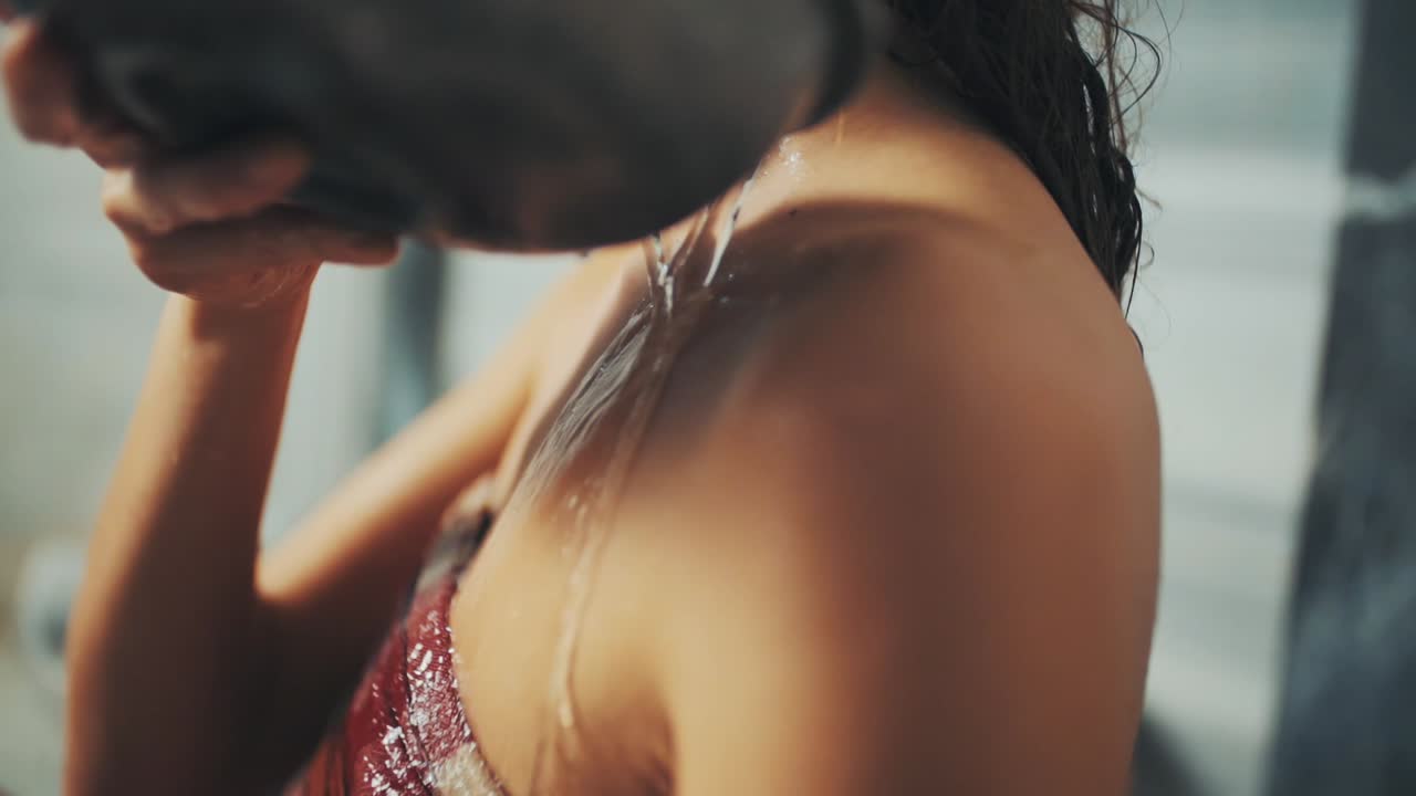 ふんどしを着た女性がトルコ式風呂で肩越しに水の入ったボウルを注ぐ