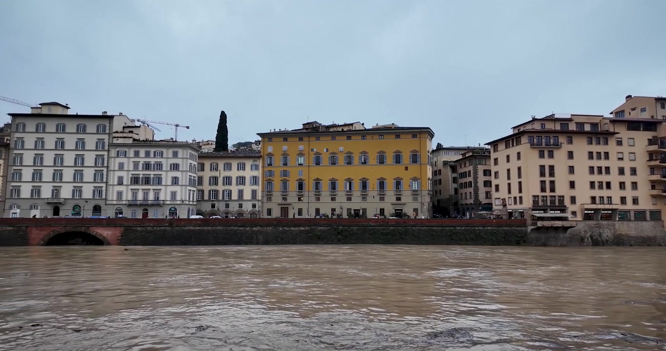 Vista panoramica del fiume Arno a Firenze, Italia, dopo giorni di piogge, con livelli dell'acqua elevati che si avvicinano a condizioni di rischio alluvione nella città storica.