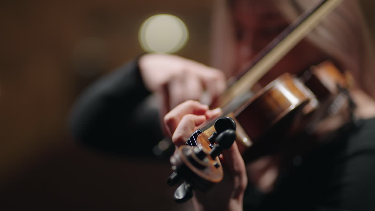 young beautiful woman is playing violin in rehearsal hall or on scene in opera house or music hall