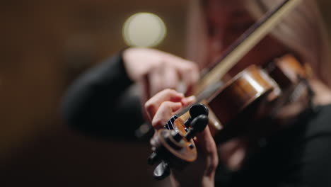 una joven hermosa está tocando el violín en la sala de ensayos o en la escena de la ópera o la sala de música.