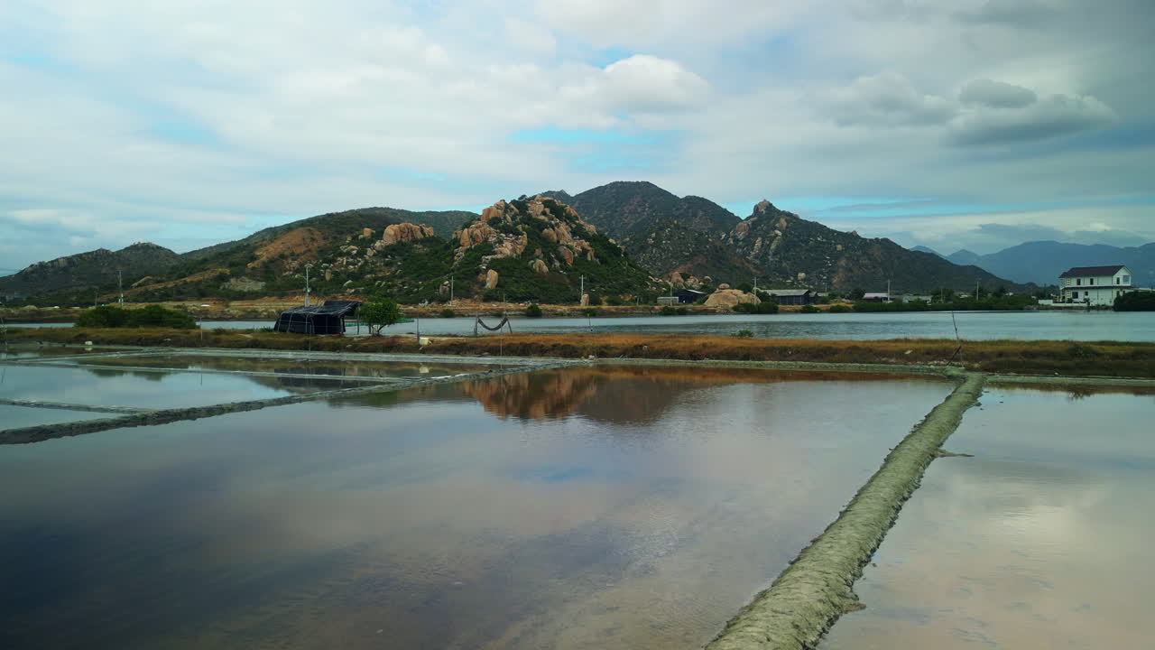 Paesaggio suggestivo di saline e montagne sotto un cielo nuvoloso