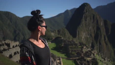 una viajera mira con admiración las ruinas de machu picchu en perú, con las colinas en forma de chocolate y las formas de animales de los andes que proporcionan un fondo impresionante.