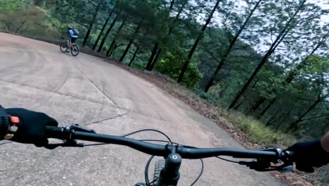 Two-bicyclists-ride-their-bicycle-on-a-road-inside-of-a-forest,-hill,-and-village-in-Guatemala,-North-America