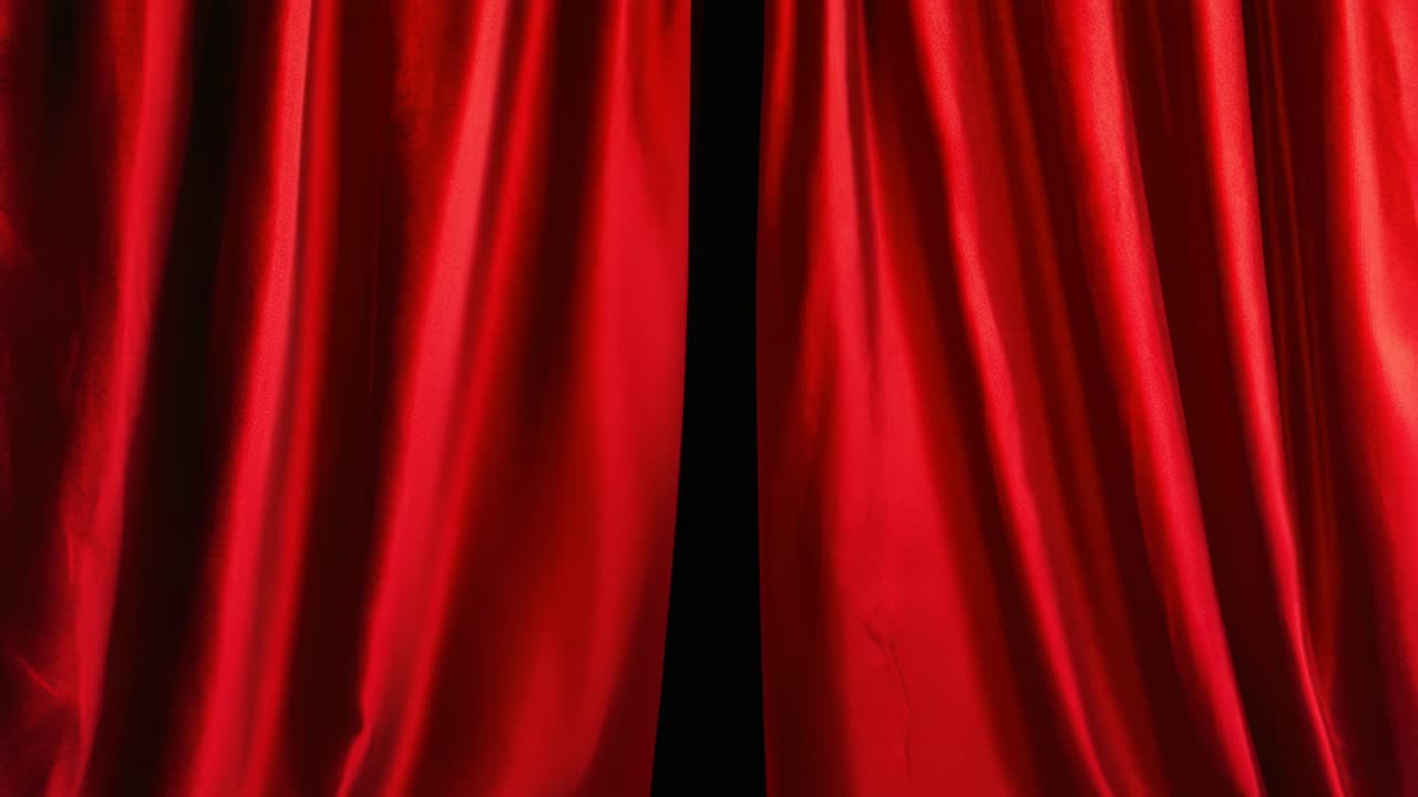 Um ângulo de vídeo dramático e em close-up de cortinas de teatro de veludo vermelho parcialmente abertas, revelando escuridão