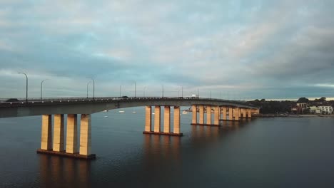 Aerial:-Drone-shot-slowly-rising-to-reveal-traffic-driving-over-a-large-bridge-whilst-commuting-to-work-during-morning-rush-hour-in-Sydney,-Australia