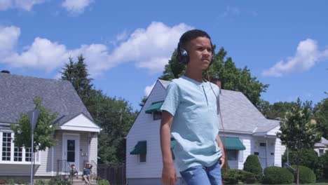 Junger-Afrikanisch-amerikanischer-Junge,-Der-Mit-Kopfhörern-Die-Straße-Hinuntergeht