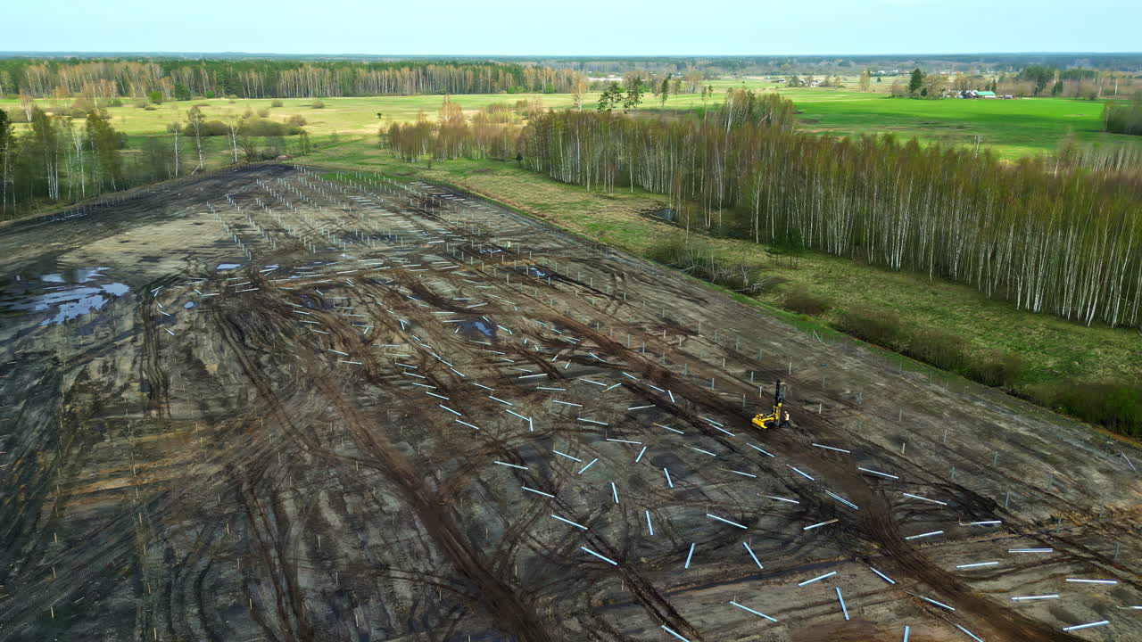 Deforested land with construction equipment amid surrounding green landscape, aerial view