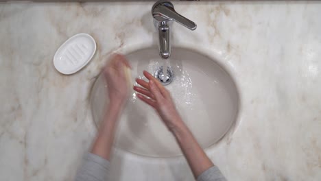 old woman's hand's are washed on tap water with soap, then rinsed and wiped on a white cloth towel - top view static close-up shot 4k