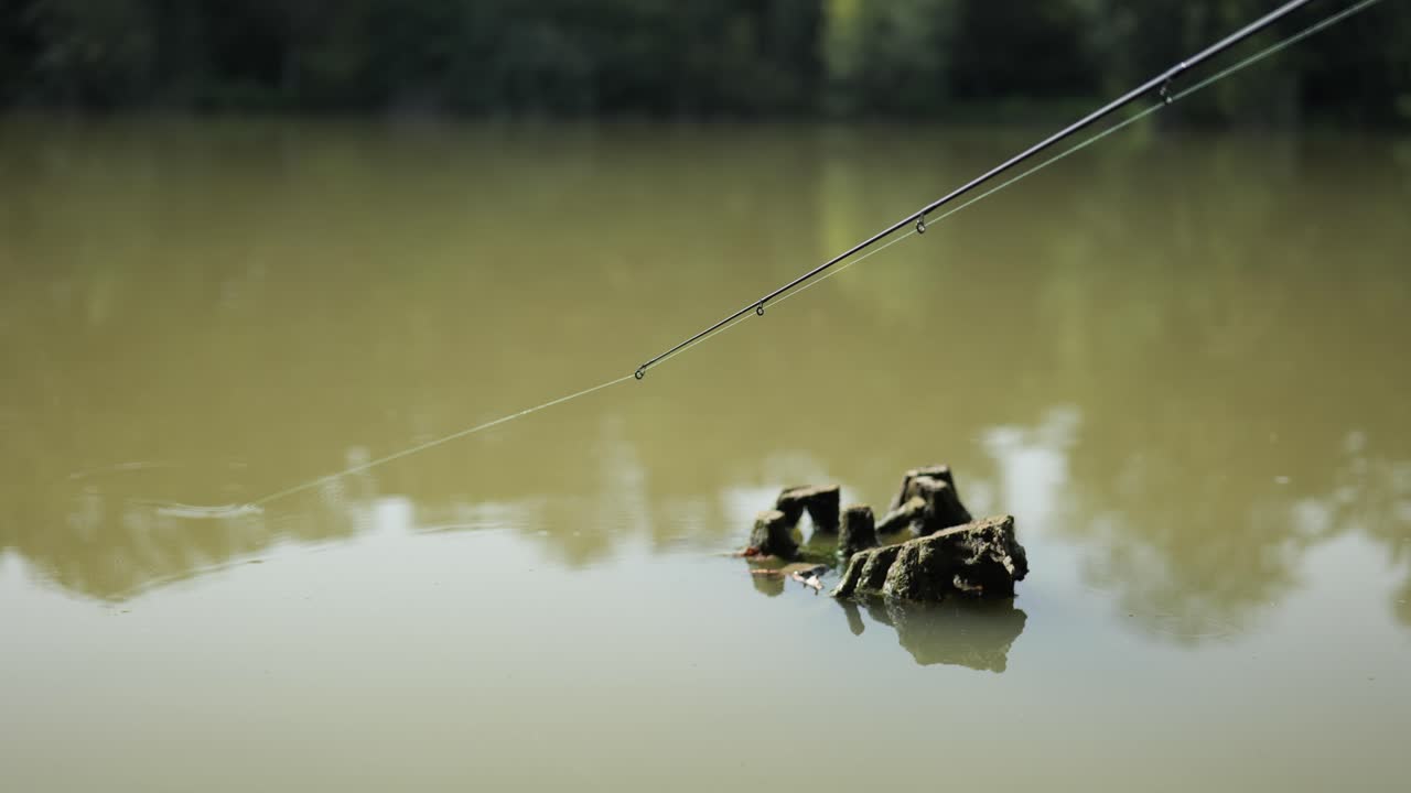 Fisk drar i flötet på utkastad fiskelina och flyr ner i grumlig sjö.