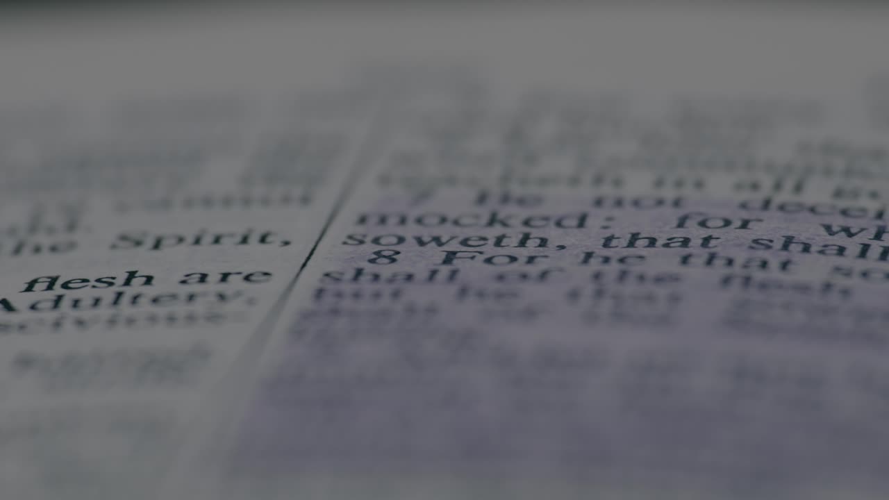 Macro shot of blurred Bible page text creates a serene and contemplative mood, with soft focus and gentle lighting enhancing quiet reflection and spiritual ambiance