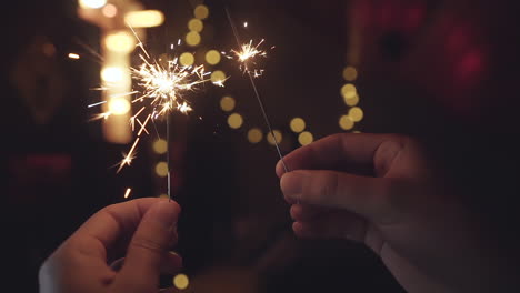 Hands-holding-bright-sparklers-burning-down-in-slow-motion