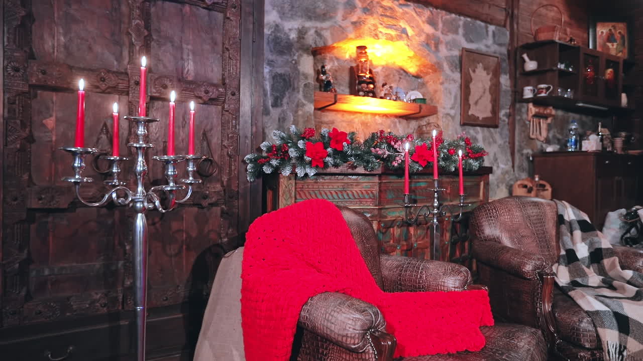 Cozy interior of living room with Christmas decorations. Christmas decorated room with many lights, candles and red light. Room with armchairs and carpet