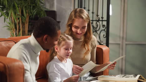 little girl shows vintage photos of relatives to black guest