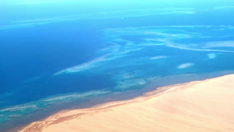 Line-between-desert-and-ocean-water,-high-altitude-aerial-view