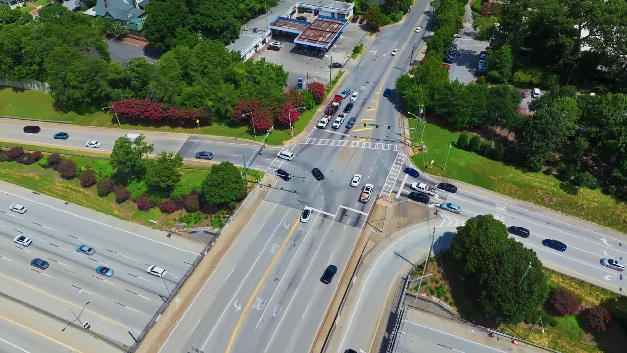 Busy traffic scene on elevated junction highway in suburb of Atlanta city, Georgia. Aerial top down. Rusty roof of service station in America