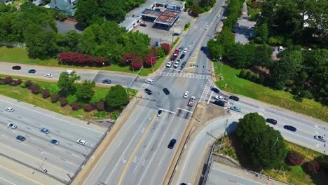 busy traffic scene on elevated junction highway in suburb of atlanta city, georgia. aerial top down. rusty roof of service station in america