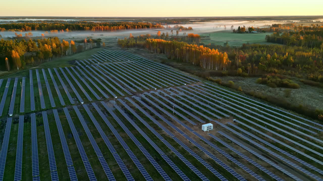 Aerial dolly shot backwards showing a wide solar panel field surrounded by autumn trees