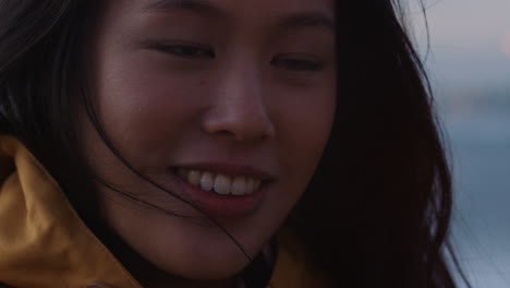 close up portrait of happy asian woman holding sparklers celebrating new years eve smiling enjoying independence day celebration on beach at sunset