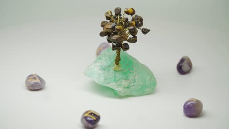 beautiful crystal tree with black gemstone on its branches surrounded by five purple crystal - close up shot