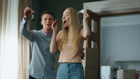 man surprising woman showing keys from new apartment. girl rejoicing moving home