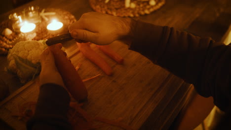 cooking food in candle light, preparing romantic dinner, hands peeling carrot close up