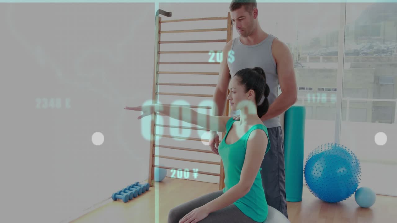 Rehab client seated on ball extending right arm, male trainer guiding lift, data tracking mobility