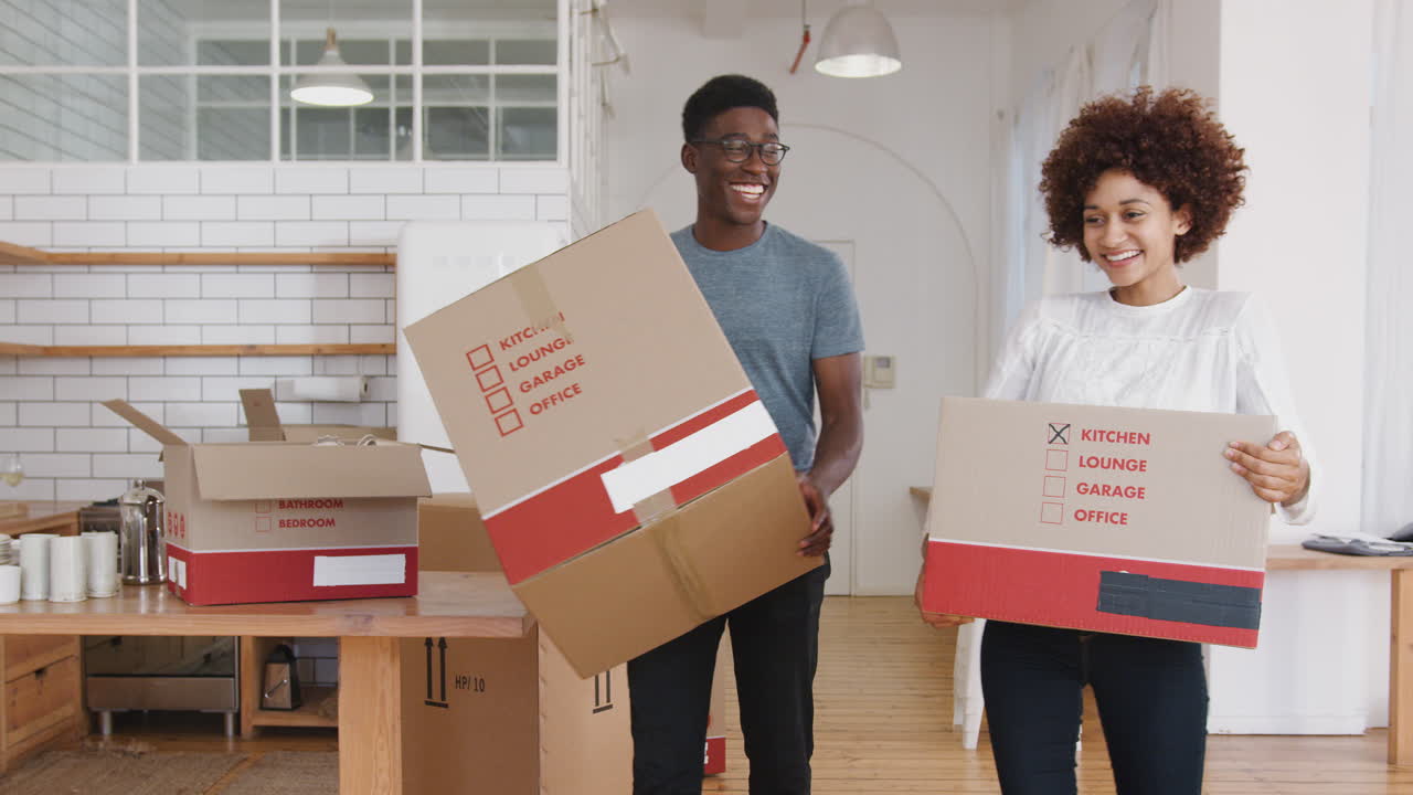 Smiling Young Couple Carrying Boxes Into New Home On Moving Day
