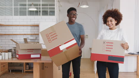 smiling young couple carrying boxes into new home on moving day