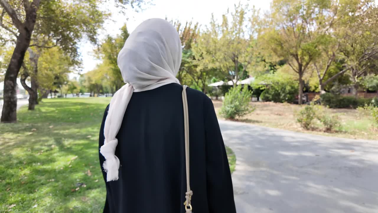 히자브 를 입은 여자 가 공원 에서 고 있다