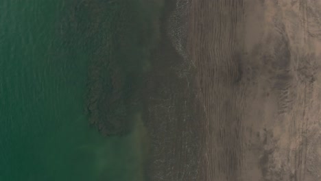 aerial birds eye view of green waves washing up on costa rica beach