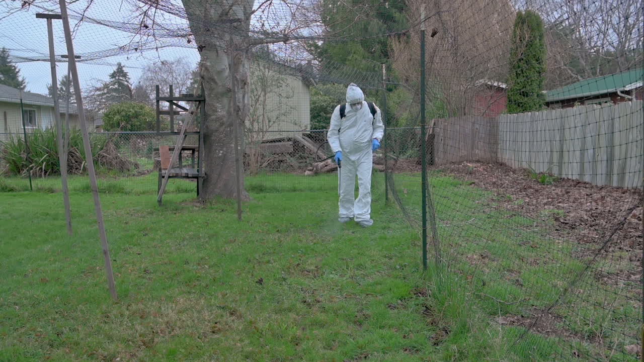 유해한 화학 물질로부터 보호 장비를 착용하고 잡초를 죽이는 스프레이를 뿌리는 남자