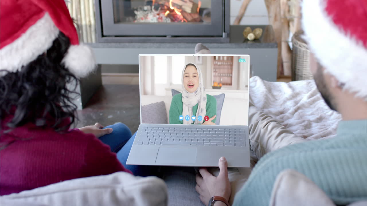 Coppia felice e mista e amica che fanno una videochiamata di Natale tramite laptop, al rallentatore