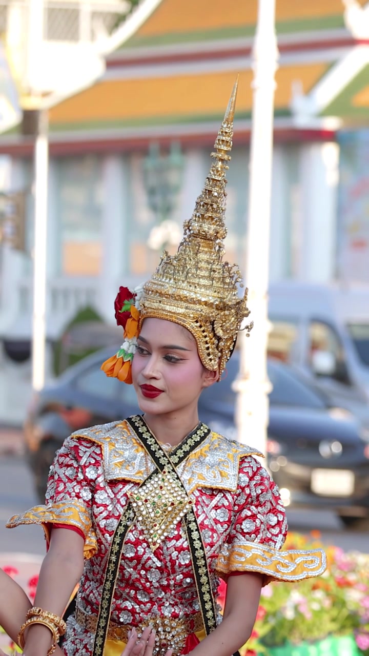 Una danzatrice in un elaborato costume dorato esegue movimenti tradizionali della danza Khon thailandese all'aperto a Bangkok.