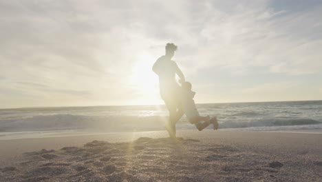 padre hispano jugando con su hijo en la playa al atardecer