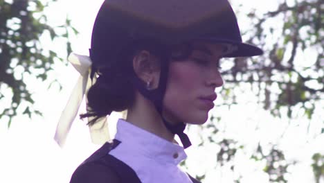 pretty young jockey girl having a horse riding lesson outdoors in a park at sunset - face closeup slow motion