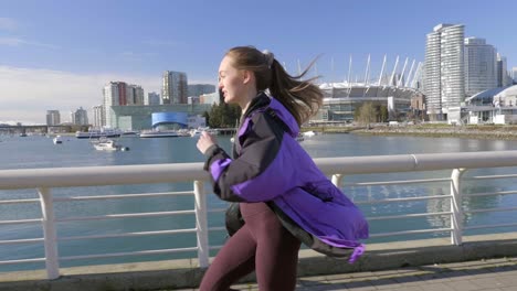 young athletic woman out running by harbour wearing jacket