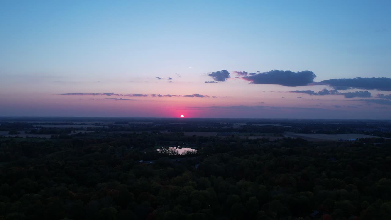 Sun disappearing over horizon at sunset in rural landscape
