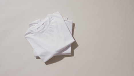 video of stack of folded white t shirts with copy space on white background