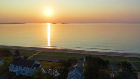 Vista-Aérea-Por-Drones-Del-Amanecer-Sobre-La-Casa-De-Playa-En-Saco-Maine-Con-Colores-Reflejándose-En-Las-Olas-Del-Océano-Y-Casas-De-Vacaciones-A-Lo-Largo-De-La-Costa-Atlántica-De-Nueva-Inglaterra