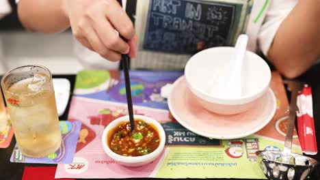 person stirring sauce with chopsticks in restaurant